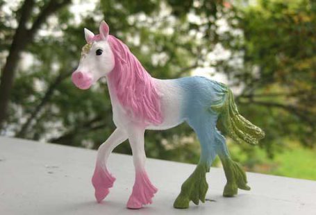 Buntes Plastik-Elfenpony vor gruenen Baeumen